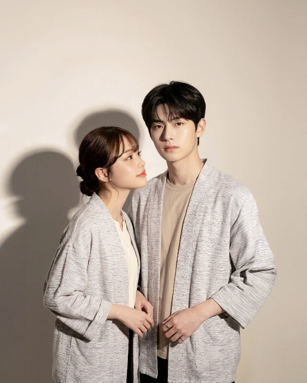 A smiling man and woman standing A couple wearing matching Hand-cranked Kimonos in Miho Matsubara colorway standing back-to-back in a garden at Grandmama Store in Hong Kong.