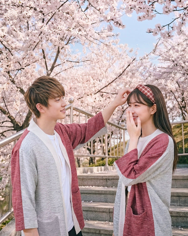 A couple wearing matching Hand-cranked Kimonos in Tokyo Tower colorway under cherry blossom trees at Grandmama Store in Hong Kong.