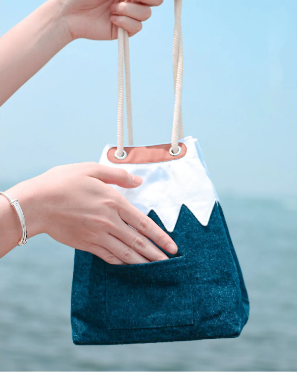 A hand opening the dark blue back slip pocket of a Mt. Fuji sake bag at Grandmama Store in Hong Kong.