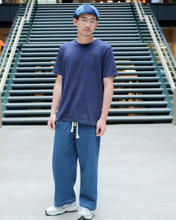 A man modeling Oxford blue Kamon Japanese Waist Rope Pants in front of a staircase at Grandmama Store in Hong Kong.