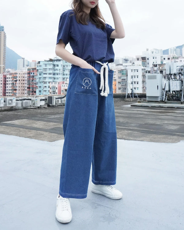 A model wearing Oxford blue Kamon Japanese Waist Rope Pants with the Mt. Fuji emblem on a rooftop at Grandmama Store in Hong Kong.