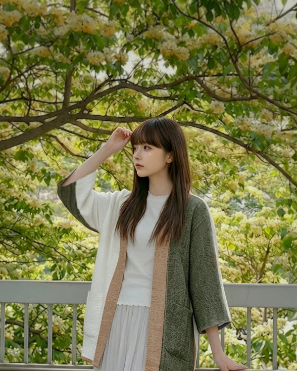 A woman modeling the Hand-cranked Kimono in Yakushima colorway outdoors under blooming trees at Grandmama Store in Hong Kong.