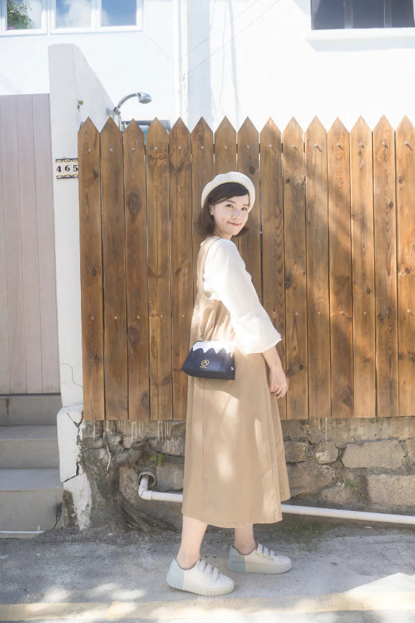 A woman modeling the dark blue Mt. Fuji Pocket Bag outdoors at Grandmama Store in Hong Kong.