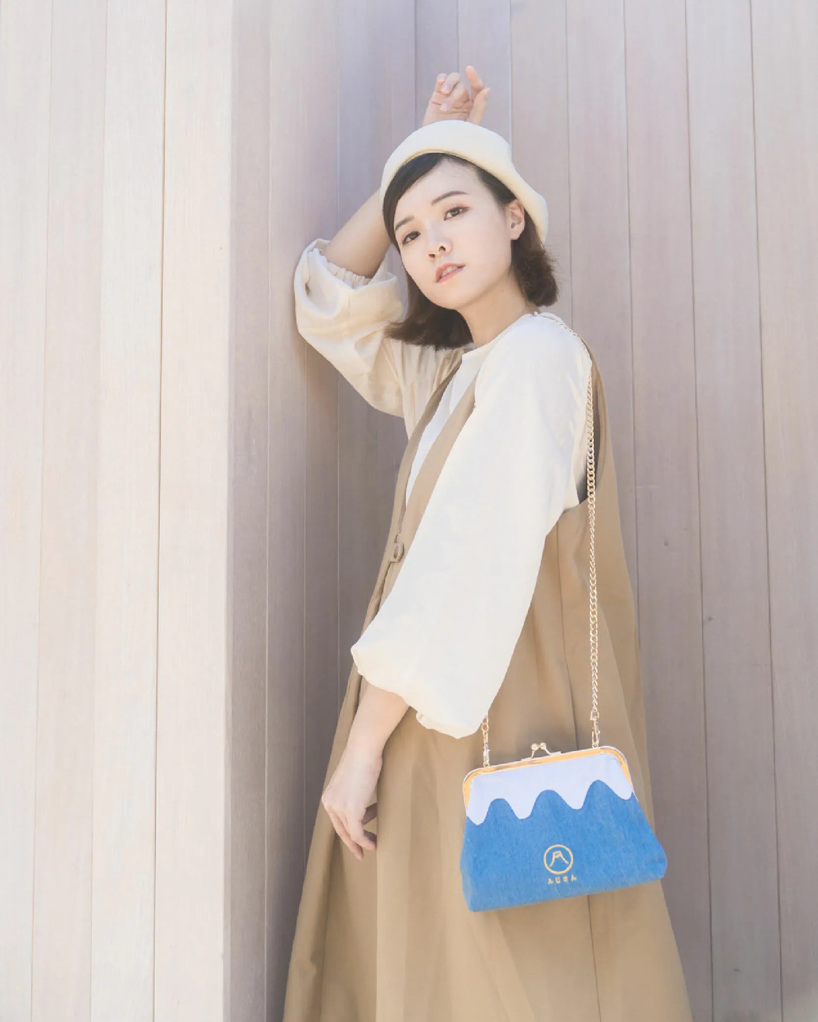 A woman modeling the light blue Mt. Fuji Pocket Bag against a wooden wall at Grandmama Store in Hong Kong.