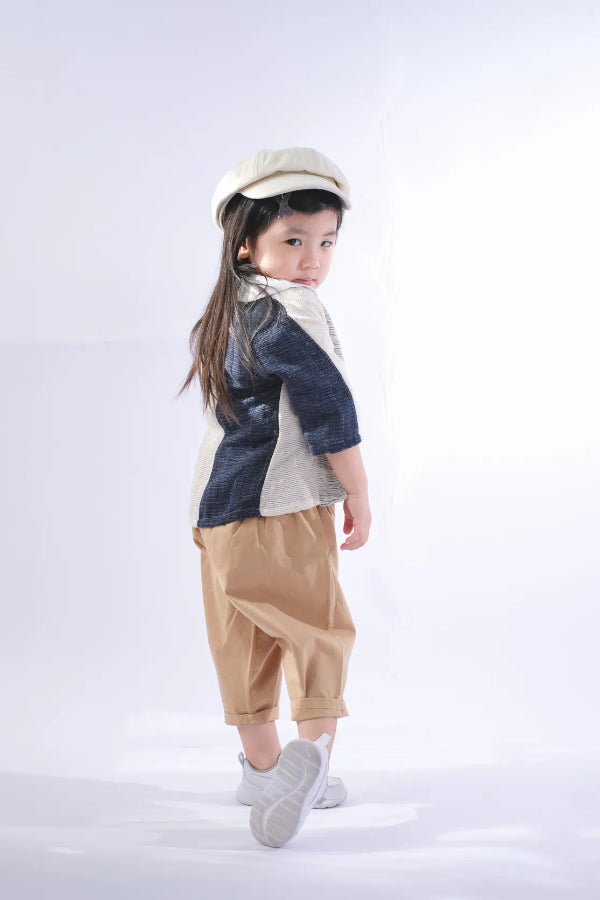 A young girl modeling a Hand-cranked Kids Kimono jacket in the Mt. Fuji navy blue and off-white colorway at Grandmama Store in Hong Kong.
