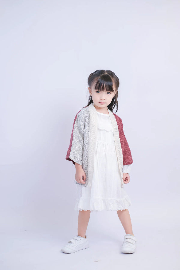 A young girl modeling a Hand-cranked Kids Kimono jacket in the Tokyo Tower red and grey colorway at Grandmama Store in Hong Kong.