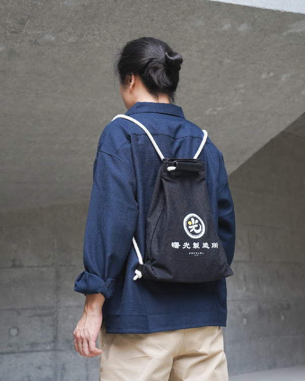 Back view of a model wearing the Light of Dawn Sake Bag in Black Denim as a backpack at Grandmama Store in Hong Kong.