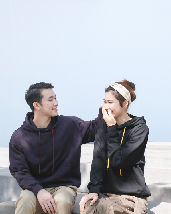 Candid moment between models wearing dark purple and black Kamon Hoodies outdoors at Grandmama Store in Hong Kong.