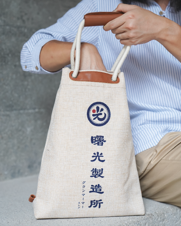 Close-up of a person holding the Light of Dawn Sake Bag in Linen at Grandmama Store in Hong Kong.