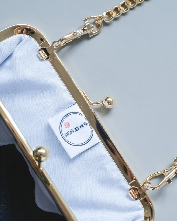 Close-up view of the open gold kiss-lock frame and interior brand label of the Mt. Fuji Pocket Bag at Grandmama Store in Hong Kong.