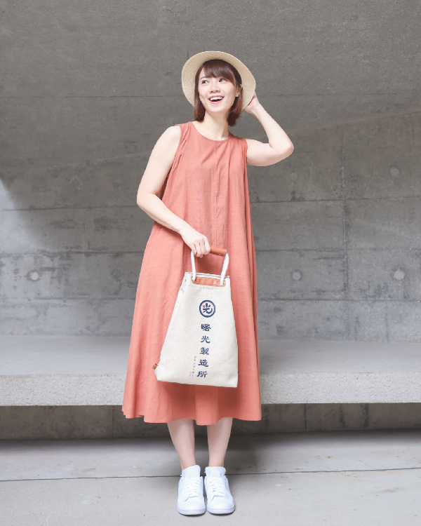 Female model holding the Light of Dawn Sake Bag in Linen at Grandmama Store in Hong Kong.