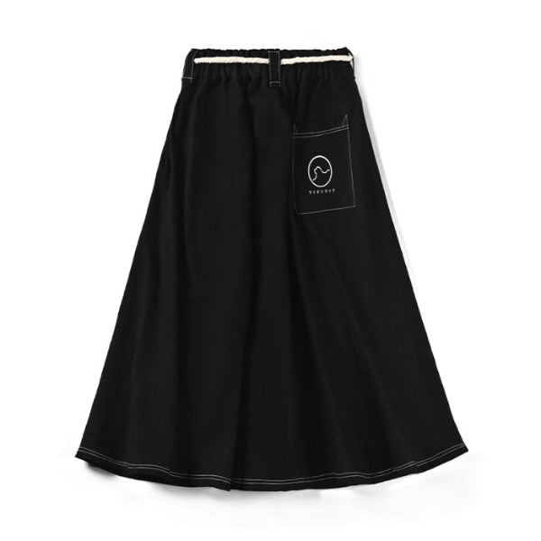 Front view flat lay of black Kamon Denim Dress-Lion Rock skirt with white rope tie and pocket logo at Grandmama Store in Hong Kong.