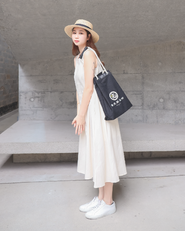 Full-length female model carrying the Light of Dawn Sake Bag in Black Denim on her shoulder at Grandmama Store in Hong Kong.