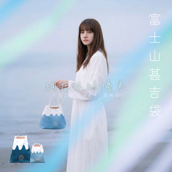 Full-length lifestyle campaign photo of a model in a white dress holding a light blue Mt. Fuji sake bag by the sea at Grandmama Store in Hong Kong.