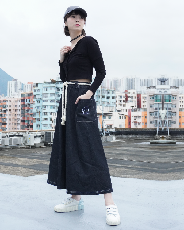 Full-length lifestyle view of a woman wearing the black Kamon Denim Dress on a rooftop at Grandmama Store in Hong Kong.