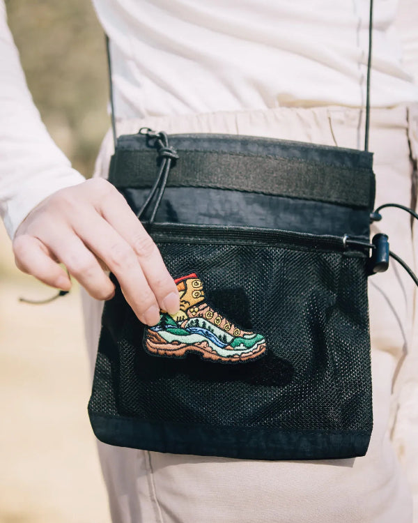 Hand attaching boot patch to black Yama Multifunctional Bag at Grandmama Store in Hong Kong.