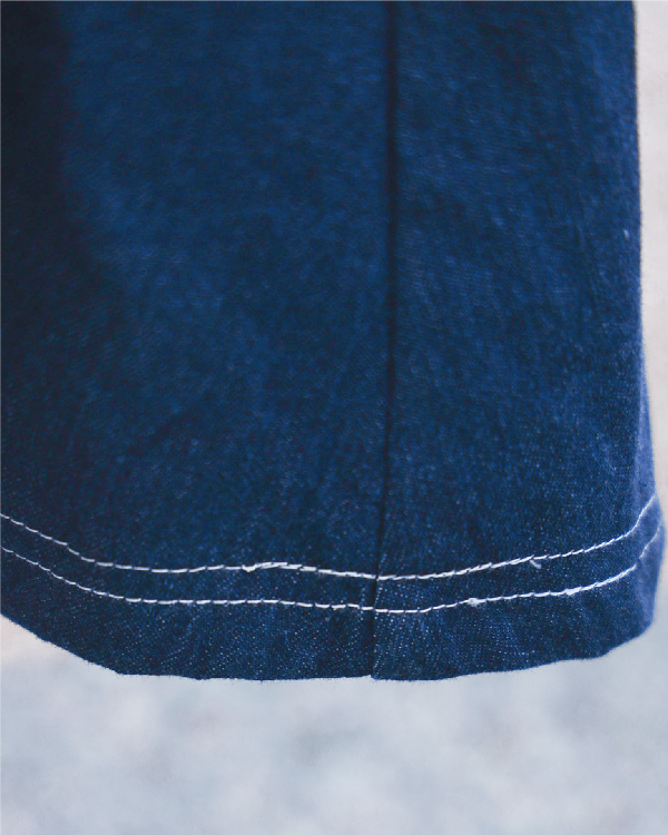 Macro close-up shot of the contrast white hem stitching on the navy blue Kamon Denim Dress-Fujisan at Grandmama Store in Hong Kong.
