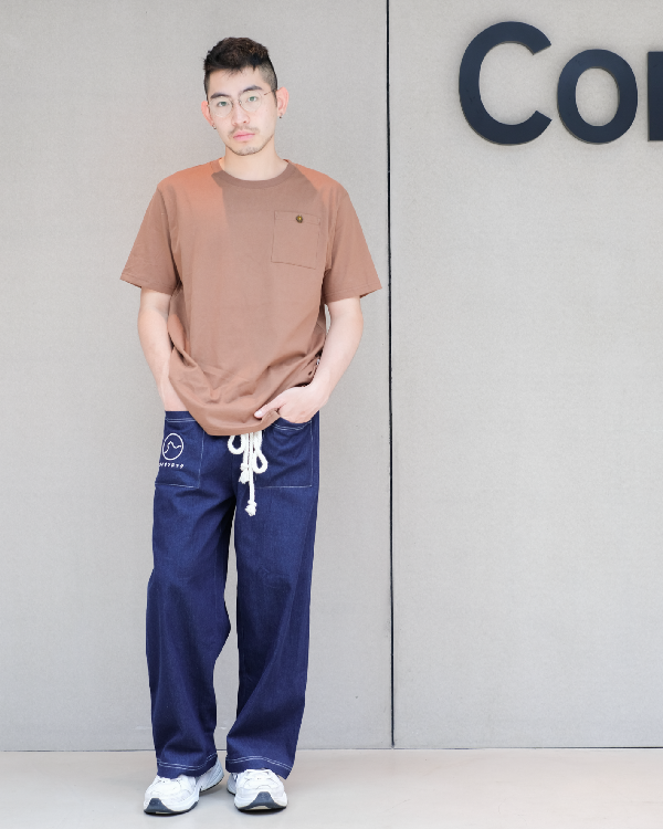 Male model standing against a grey wall wearing navy blue Kamon Japanese Waist Rope Pants with Lion Rock pocket detail at Grandmama Store in Hong Kong.