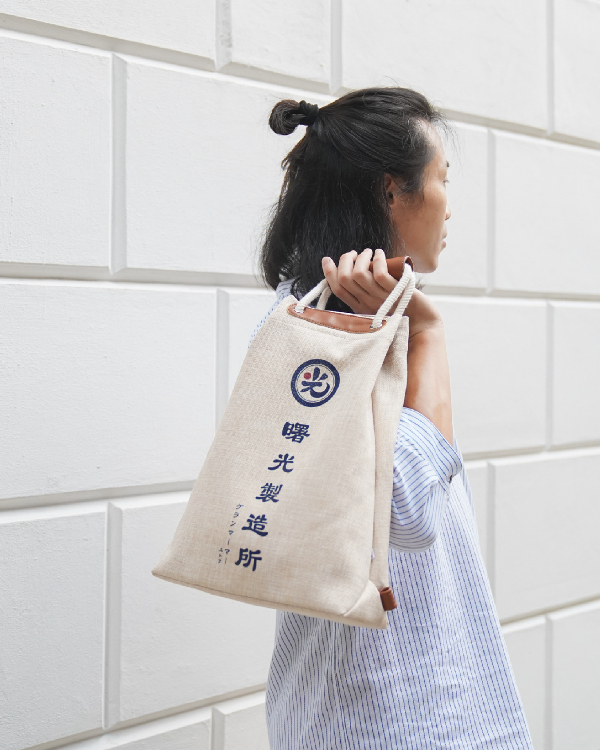 Model carrying the Light of Dawn Sake Bag in Linen over their shoulder at Grandmama Store in Hong Kong.
