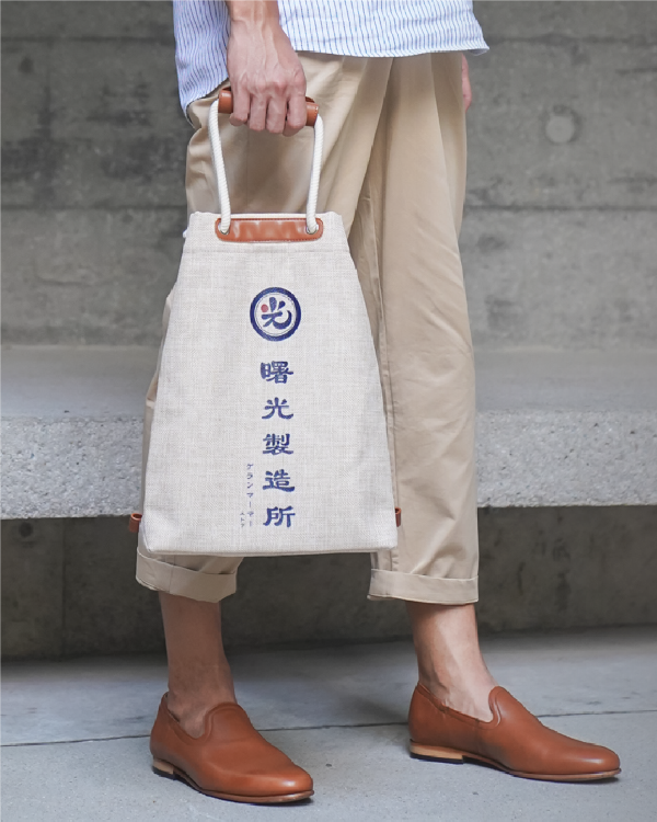 Model holding the Light of Dawn Sake Bag in Linen by hand at Grandmama Store in Hong Kong.
