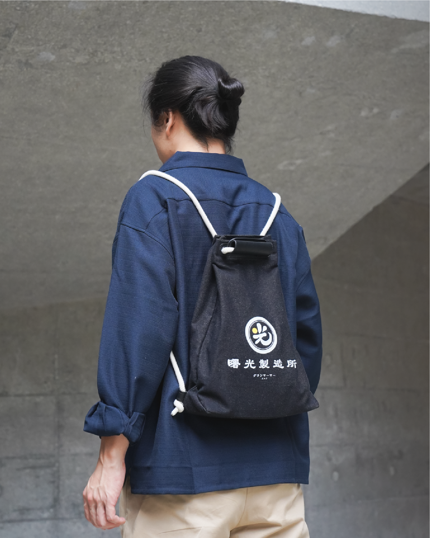 Model wearing the Light of Dawn Sake Bag in Black Denim as a backpack at Grandmama Store in Hong Kong.