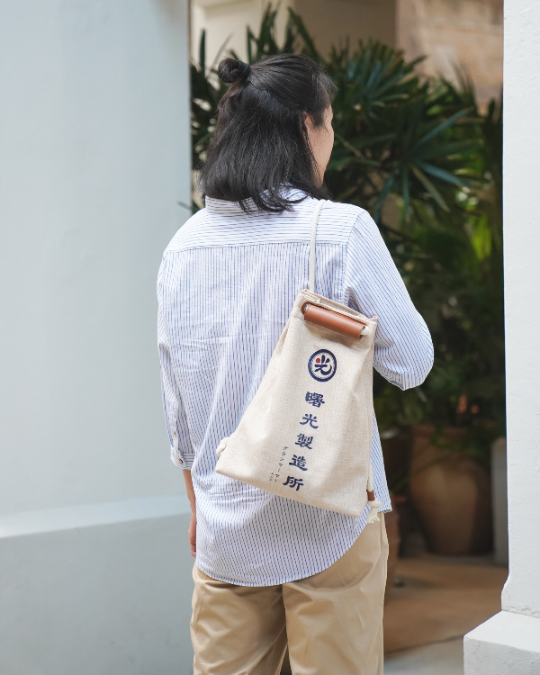 Model wearing the Light of Dawn Sake Bag in Linen over one shoulder at Grandmama Store in Hong Kong.