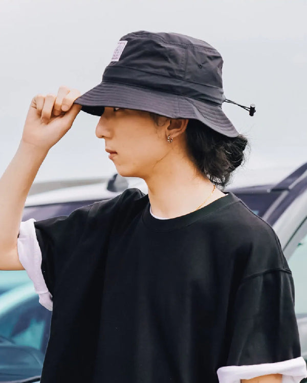 Model wearing the black Yama Workwear Bucket Hat outdoors at Grandmama Store in Hong Kong.