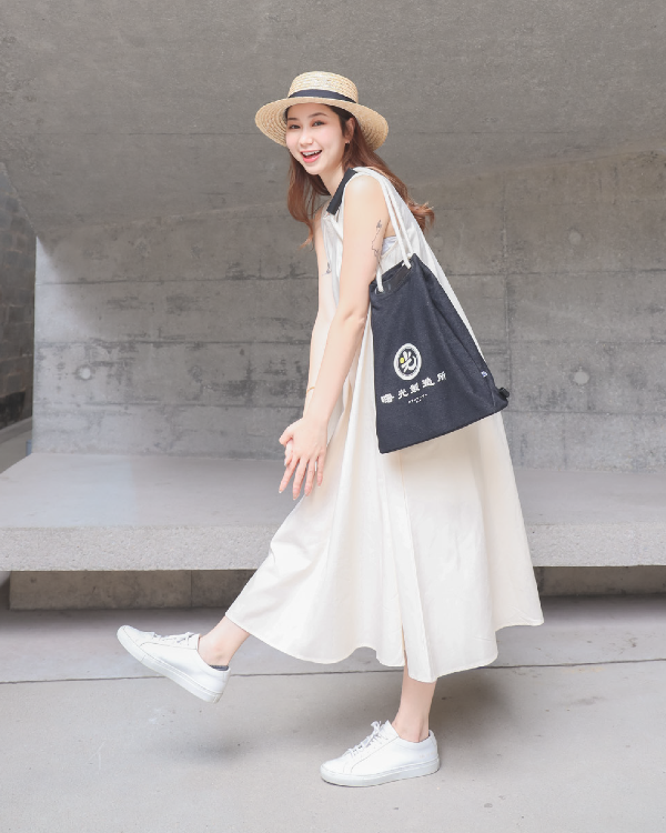 Playful female model carrying the Light of Dawn Sake Bag in Black Denim over her shoulder at Grandmama Store in Hong Kong.