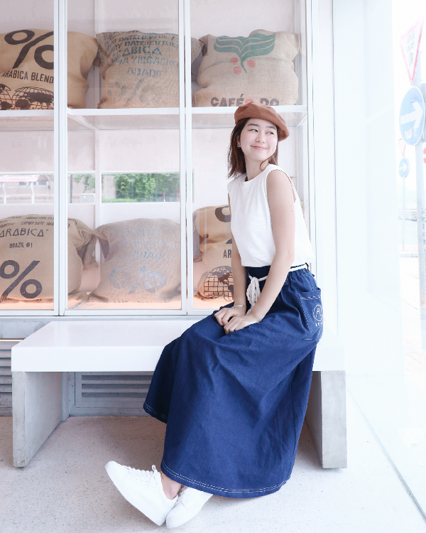 Woman in a brown beret sitting on a bench wearing the navy blue Kamon Denim Dress-Fujisan at Grandmama Store in Hong Kong.