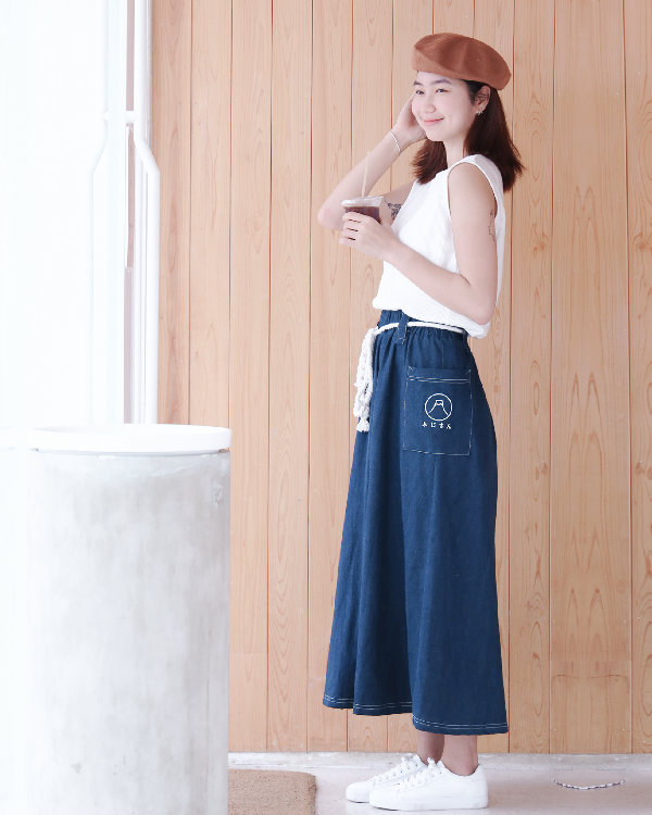 Woman in a brown beret wearing the navy blue Kamon Denim Dress-Fujisan holding iced coffee at Grandmama Store in Hong Kong.