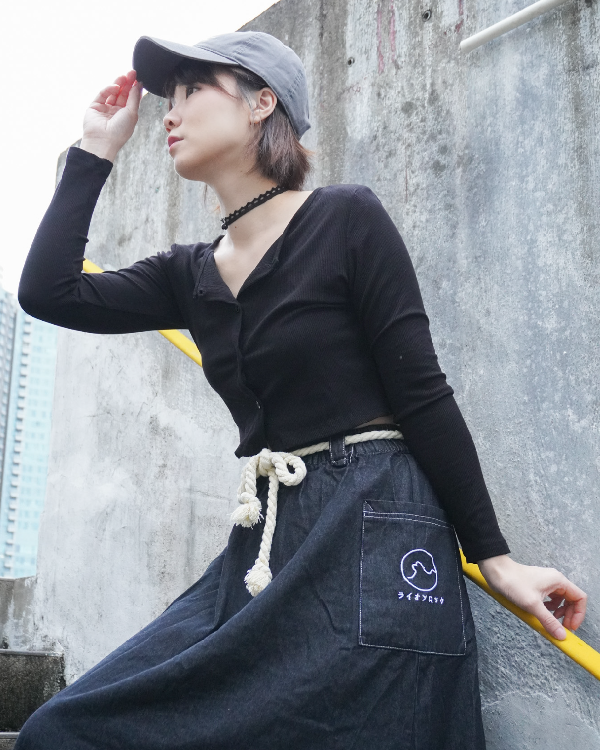 Woman in a grey cap wearing the black Kamon Denim Dress with braided rope belt on outdoor stairs at Grandmama Store in Hong Kong.