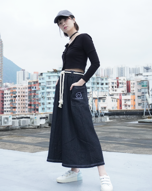 Woman modeling the black Kamon Denim Dress and baseball cap on an urban rooftop at Grandmama Store in Hong Kong.