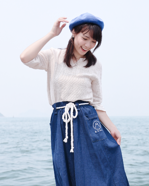 Woman wearing the navy blue Kamon Denim Dress-Fujisan and blue beret near the ocean at Grandmama Store in Hong Kong.
