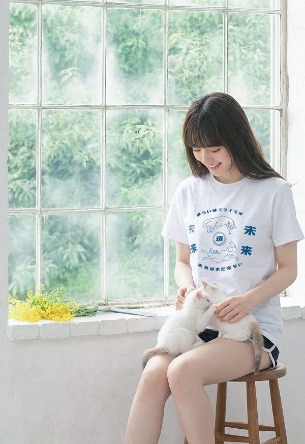 Woman wearing the white Lazy Cat Tee sitting by a window playing with kittens at Grandmama Store in Hong Kong.